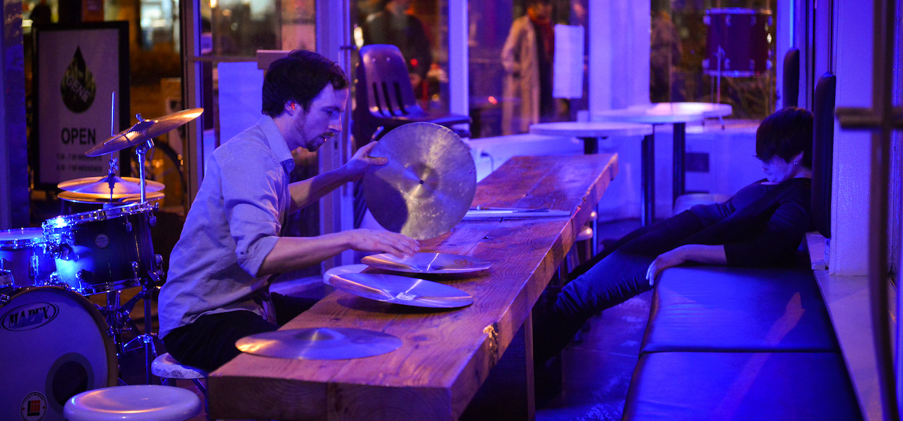 Ben Brown playing cymbals on a table during a performance.