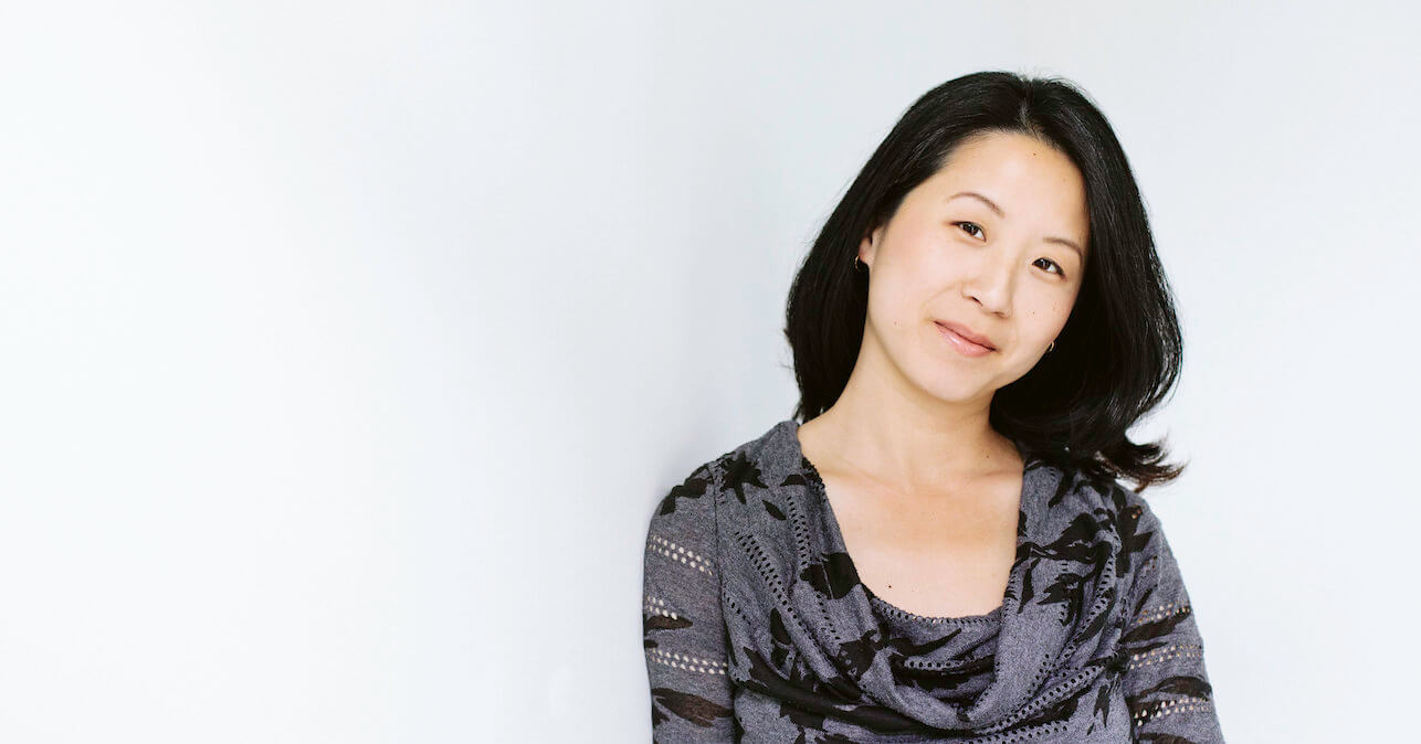 Grace Huang with a slight smile and head tilted, wearing a grey and black shirt.