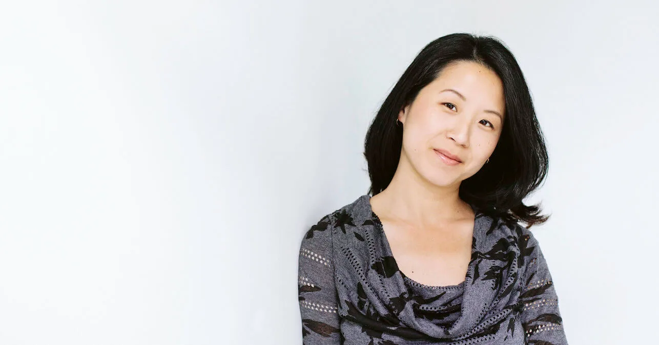 Grace Huang with a slight smile and head tilted, wearing a grey and black shirt.