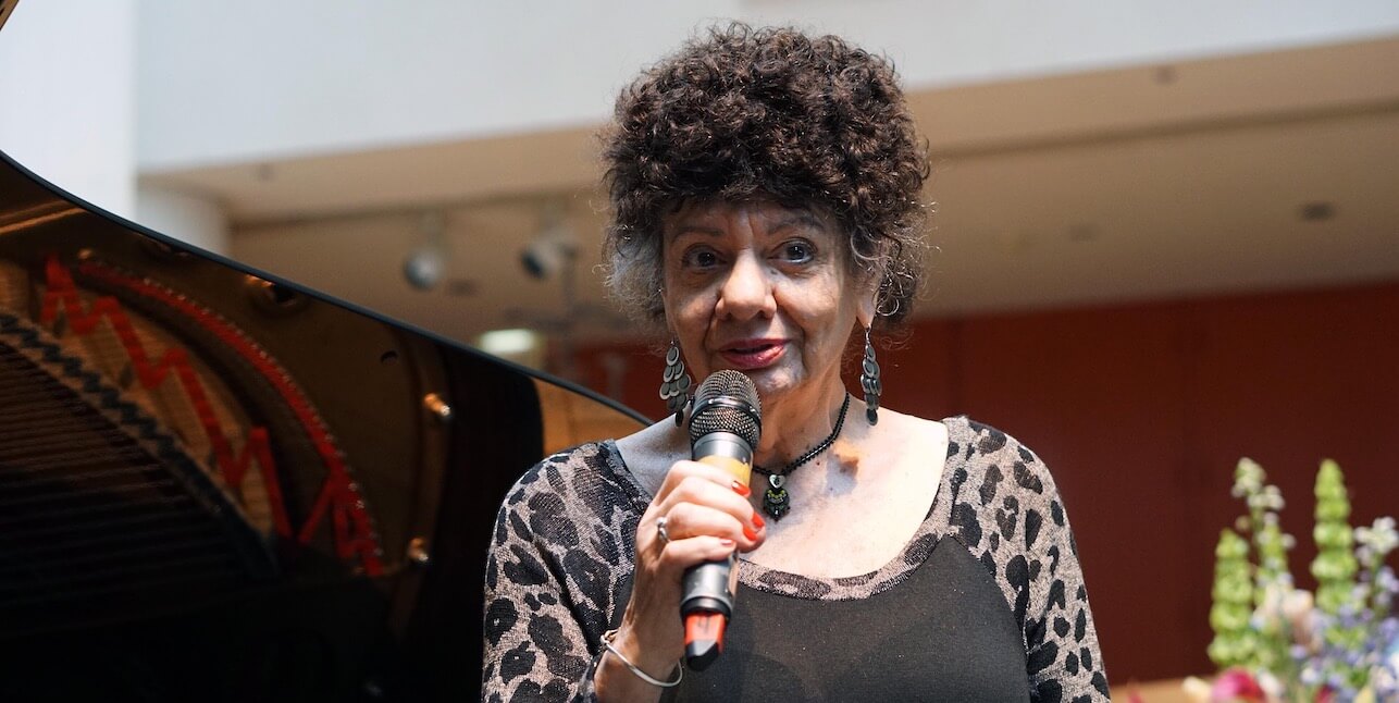 Jay Clayton in a leopard print and black shirt, holding a microphone