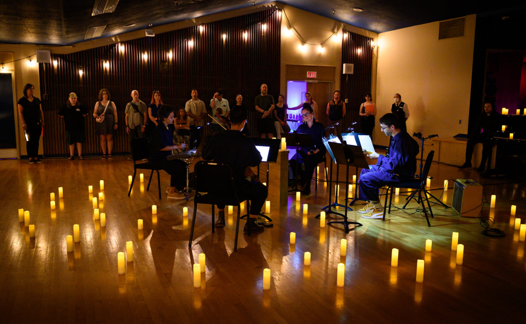 Aram and other performers in The Tempest Project, circled by many candles while performing.