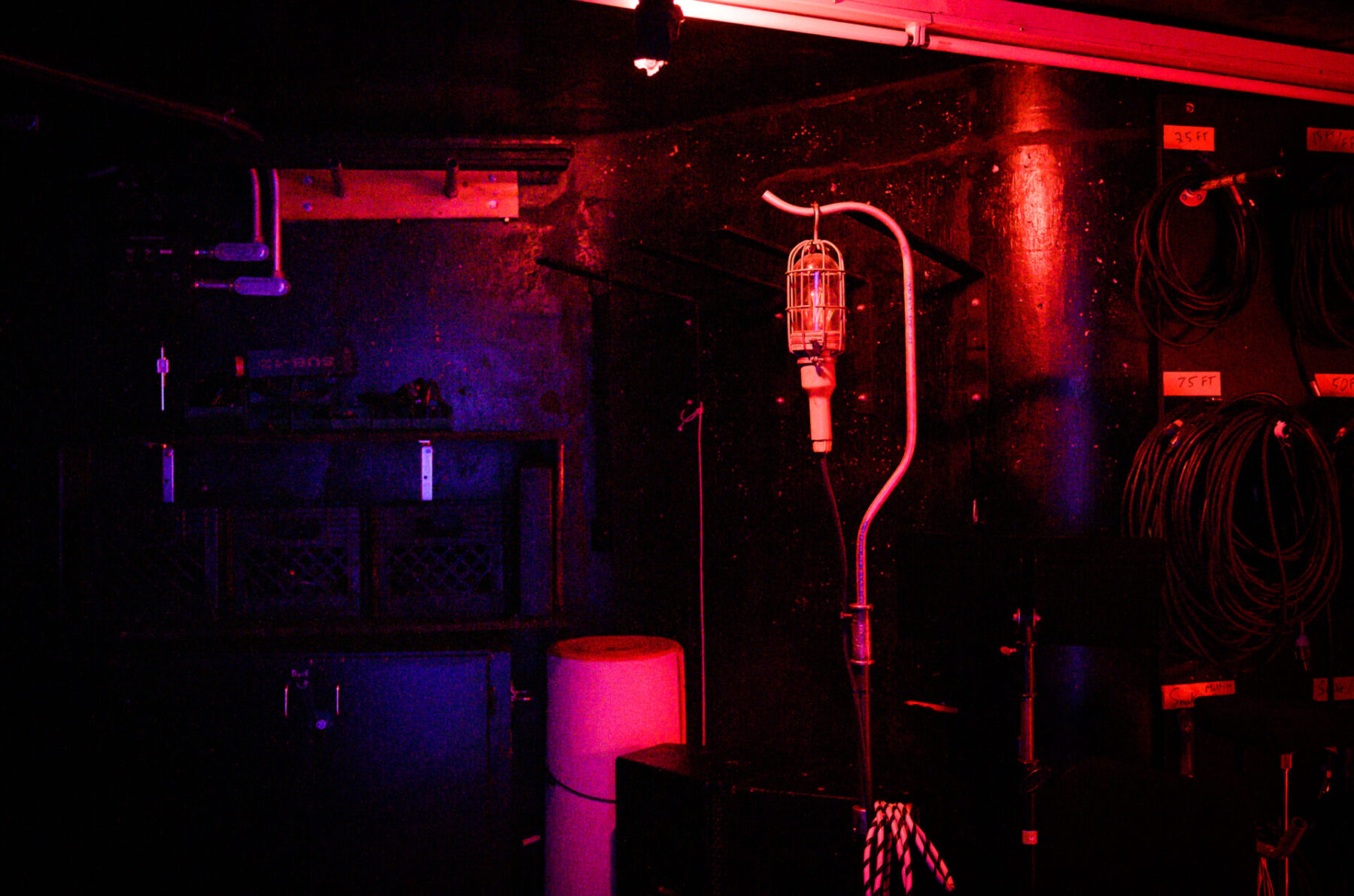 A backstage photo of a lamp in a black room with red light shining around.