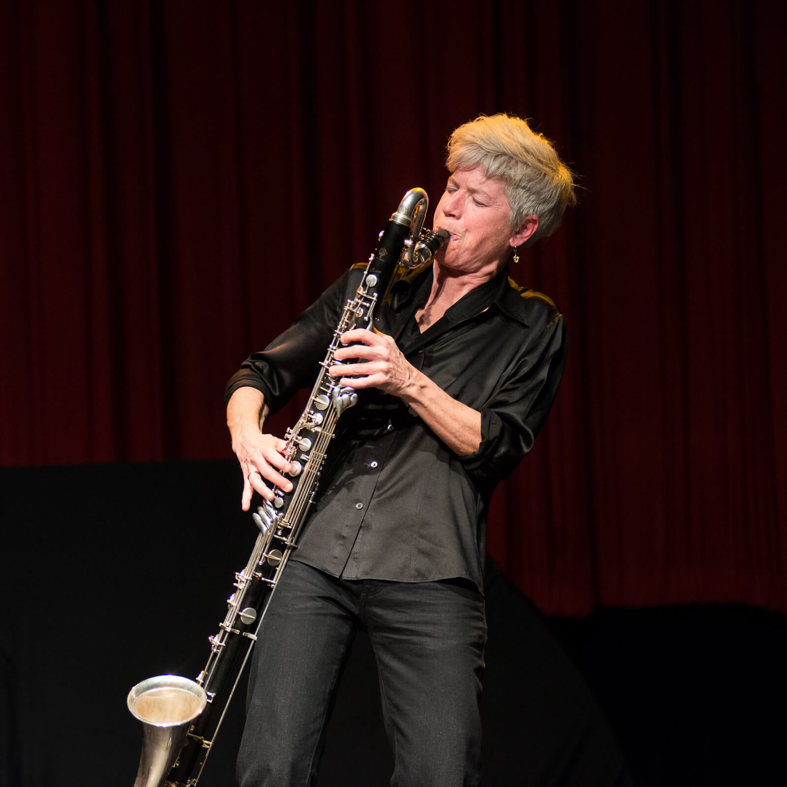 Lori Freedman in a black shirt and pants, playing the clarinet