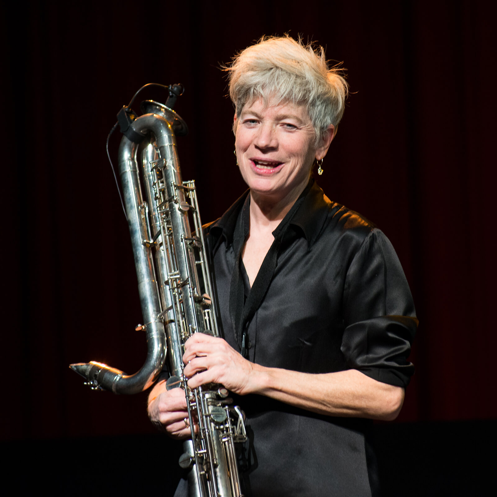 Lori Freedman in a shiny black shirt smiling while holding her clarinet.