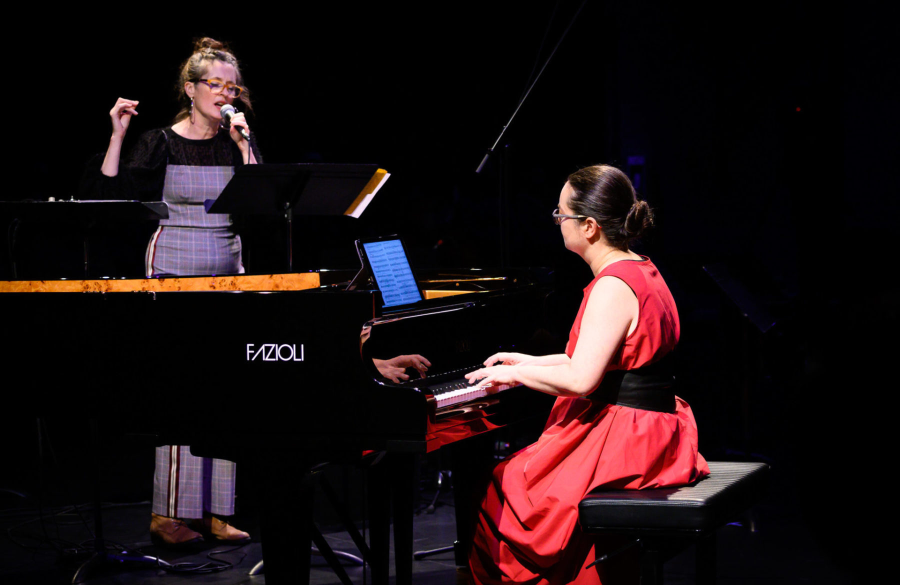 Rachel Kiyo Iwaasa playing the piano while Julia Ulehla sings beside the piano