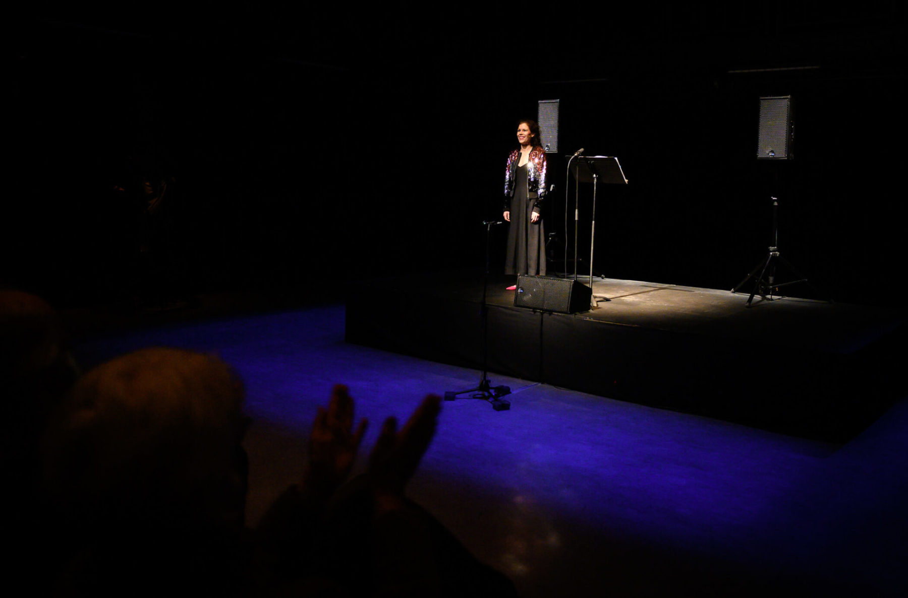 Dory Hayley standing on stage with a spotlight on her and a purple light in front