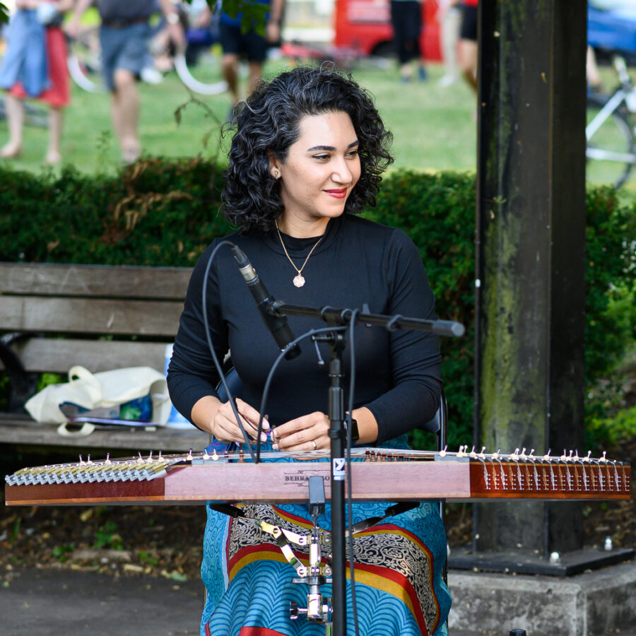 Saina Khaledi, santour player, smiling and playing in an outdoor concert