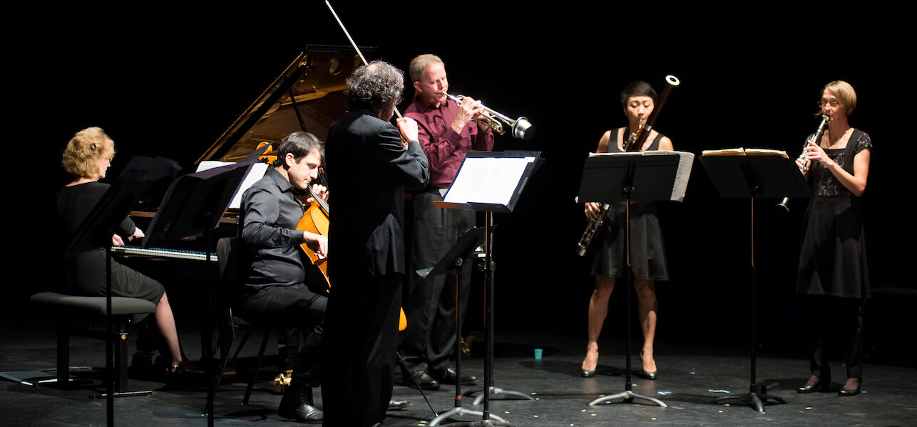 Turning Point Ensemble standing in a semi-circle, performing.