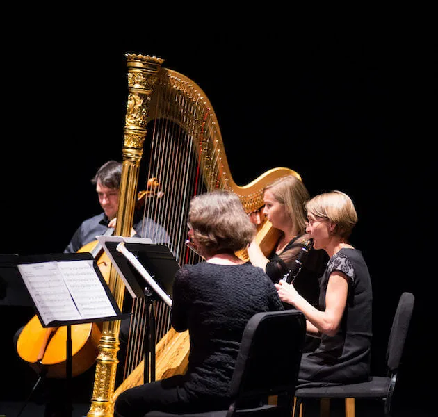 Turning Point Ensemble standing in a semi-circle, performing.