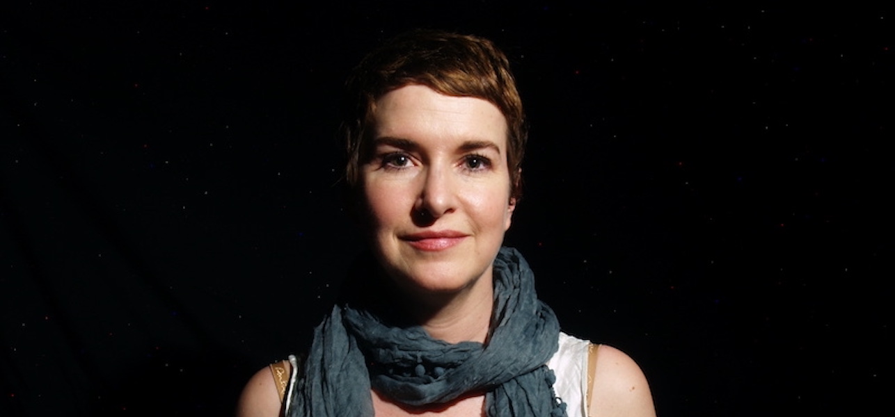 A close up headshot photo of Viviane Houle, staring at the camera, wearing a green scarf.